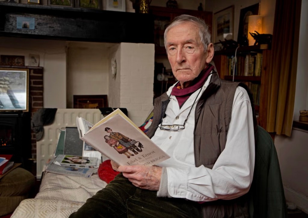 Raymond looking at the camera while holding the graphic novel he made of his parents